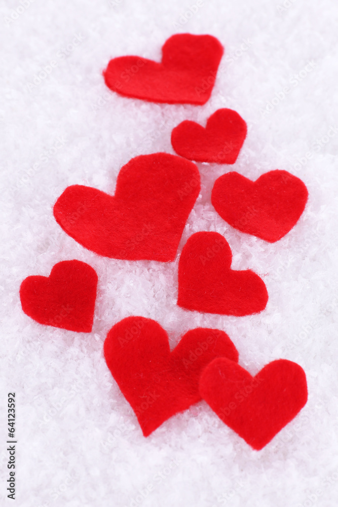 Little felt hearts on snowy background