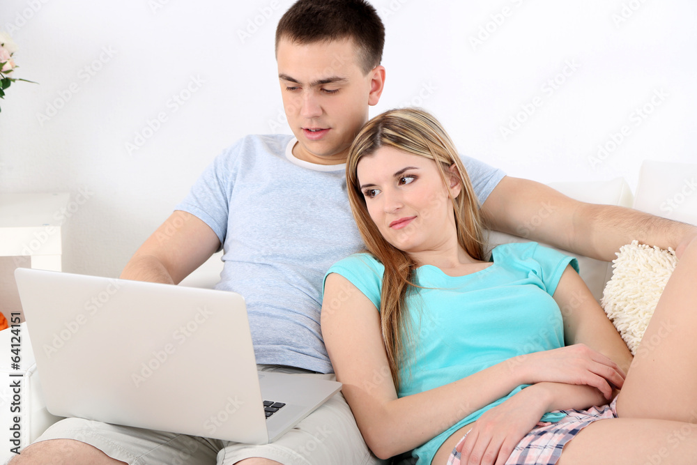 Loving couple relaxing with laptop, on home interior Loving couple relaxing with laptop, on home interior