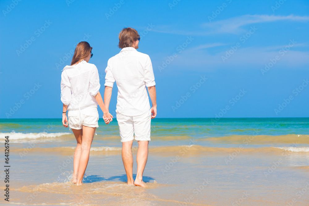 couple in white standing on beach looking at the sea couple in white standing on beach looking at the sea