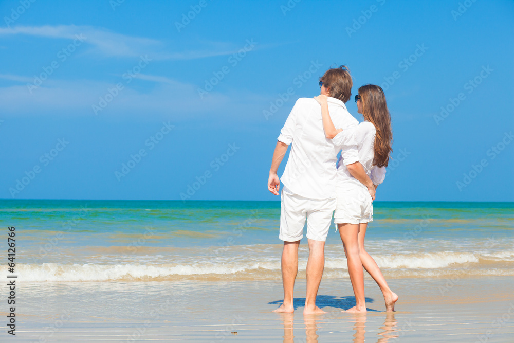 couple in white hugging on beach