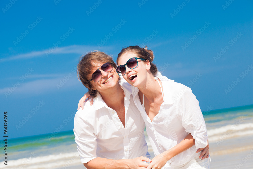 couple in sunglasses in white clothes smiling outdoors
