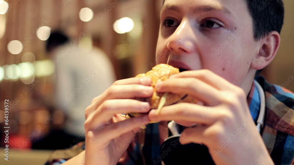Young teenager eating tasty hamburger in fast food restaurant Young teenager eating tasty hamburger in fast food restaurant