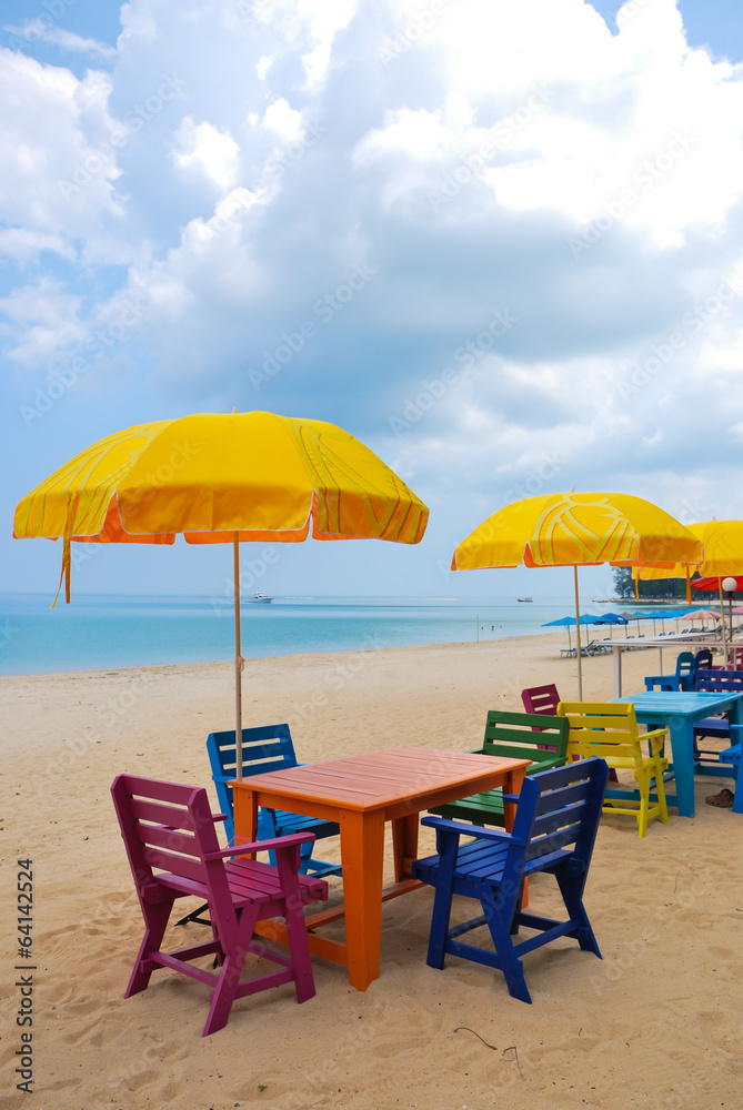 Colorful chair and table with yellow umbrella on the beach