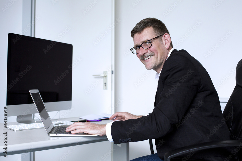 man sitting at desk and smiling man sitting at desk and smiling