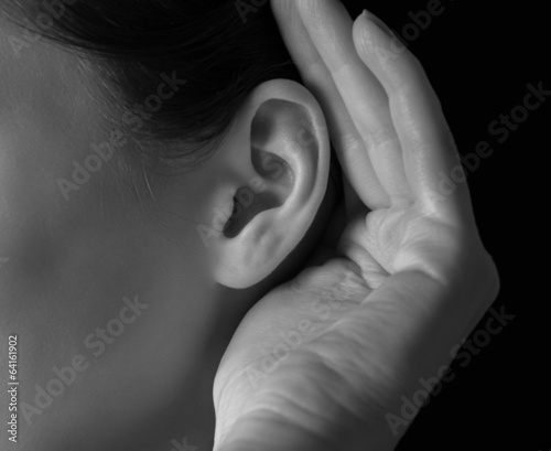 Woman holds her hand near ear photo