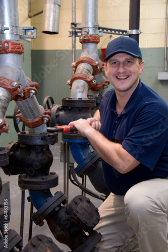 Plumber with wrench repairs pipes and valve