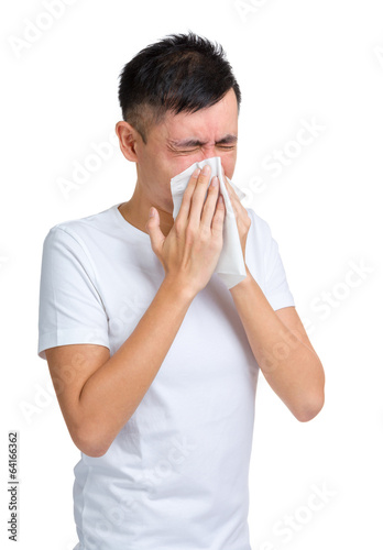 Young man blowing nose using tissue