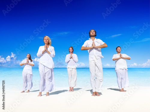 People performing yoga on the beach