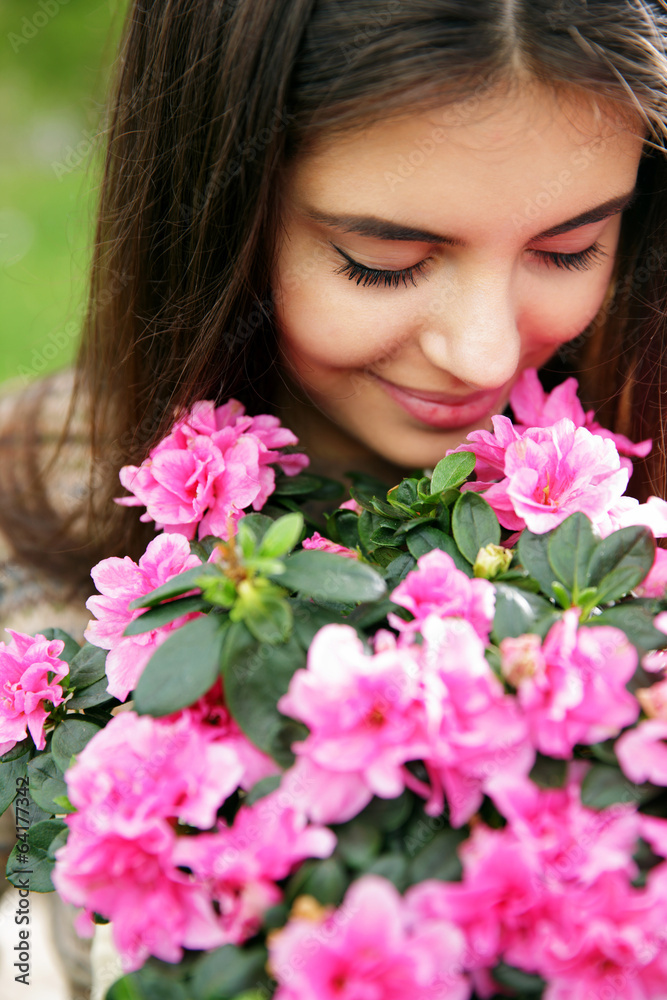 Young woman smelling pink flowers
