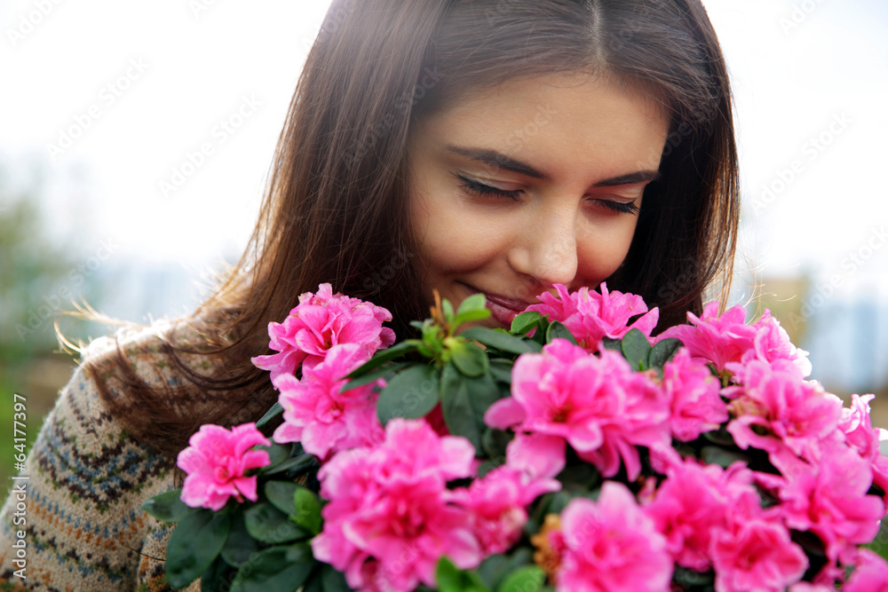 Portrait of a young happy woman smelling pink flowers Portrait of a young happy woman smelling pink flowers