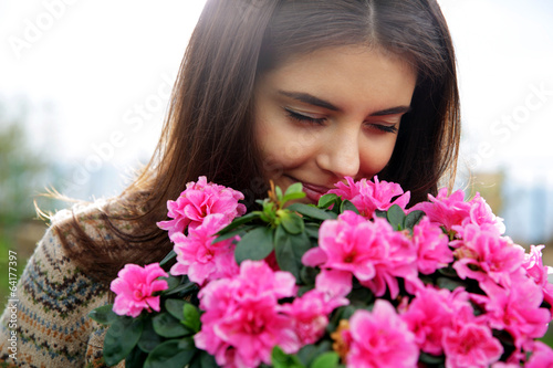 Portrait of a young happy woman smelling pink flowers