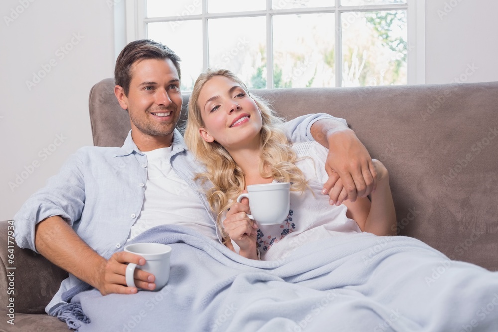 Relaxed loving couple with coffee cups in living room Relaxed loving couple with coffee cups in living room