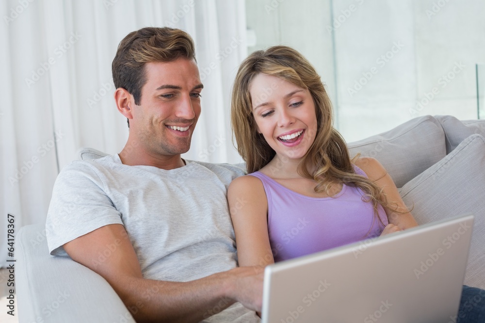 Relaxed couple using laptop on couch Relaxed couple using laptop on couch