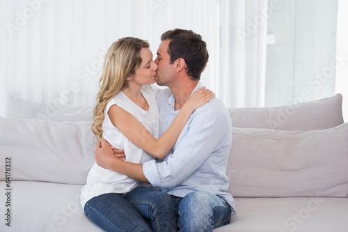 Loving couple sitting and kissing on couch