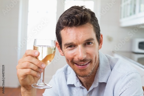 Smiling man holding a wine glass at home