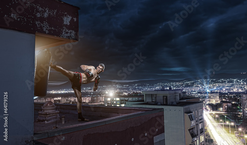 Young man boxing training , on top of the house above the city