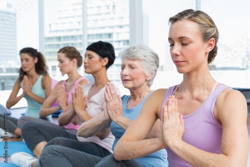 Class sitting with joined hands in a row at yoga class