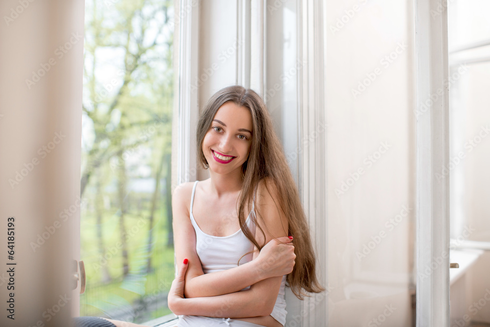 Pretty and cute girl sitting near the window on the windowsill h Pretty and cute girl sitting near the window on the windowsill h