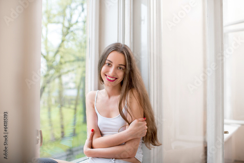 Pretty and cute girl sitting near the window on the windowsill h Free Download Pretty and cute girl sitting near the window on the windowsill h - GFXLoad