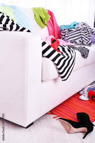 Messy colorful clothing on  sofa on light background photo