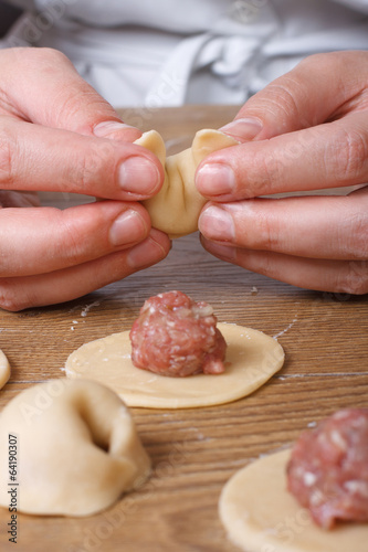 Hands cooks prepare dumplings close-up vertical