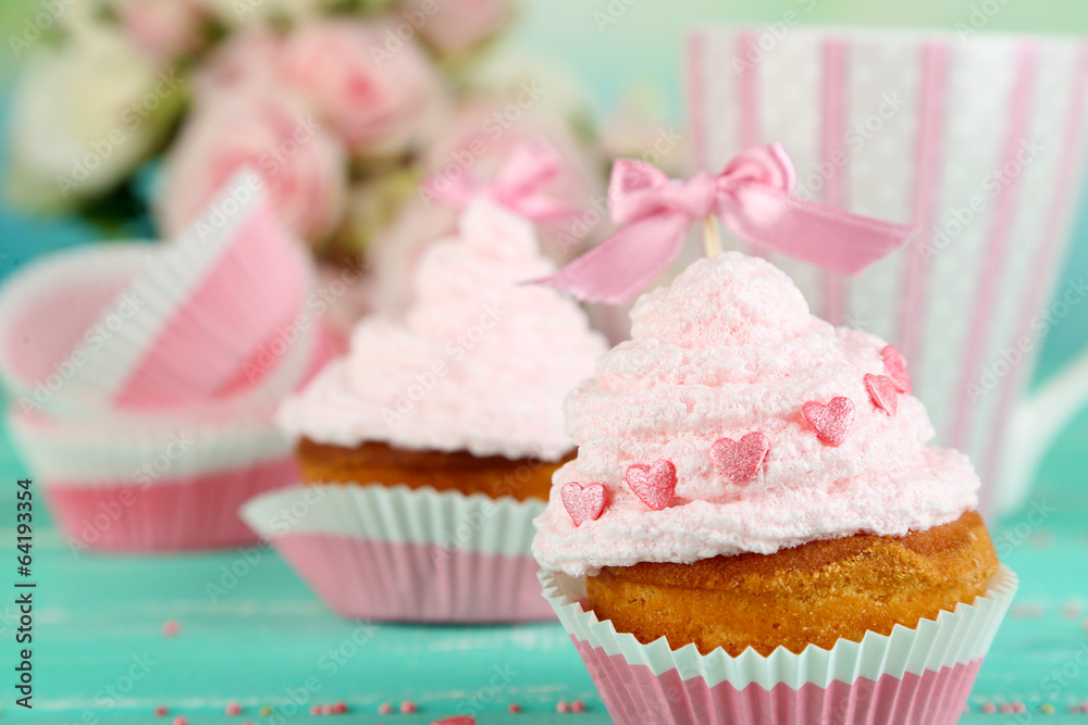 Tasty cup cakes with cream on blue wooden table