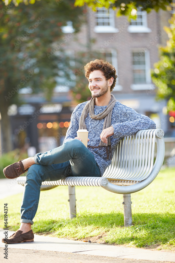 Obraz premium Man Relaxing On Park Bench With Takeaway Coffee
