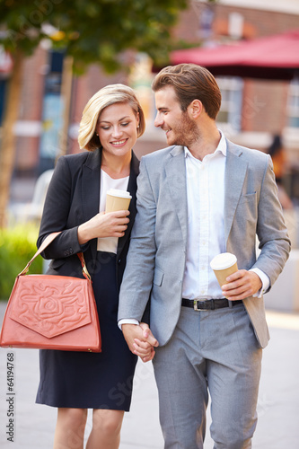Business Couple Walking Through Park With Takeaway Coffee photo