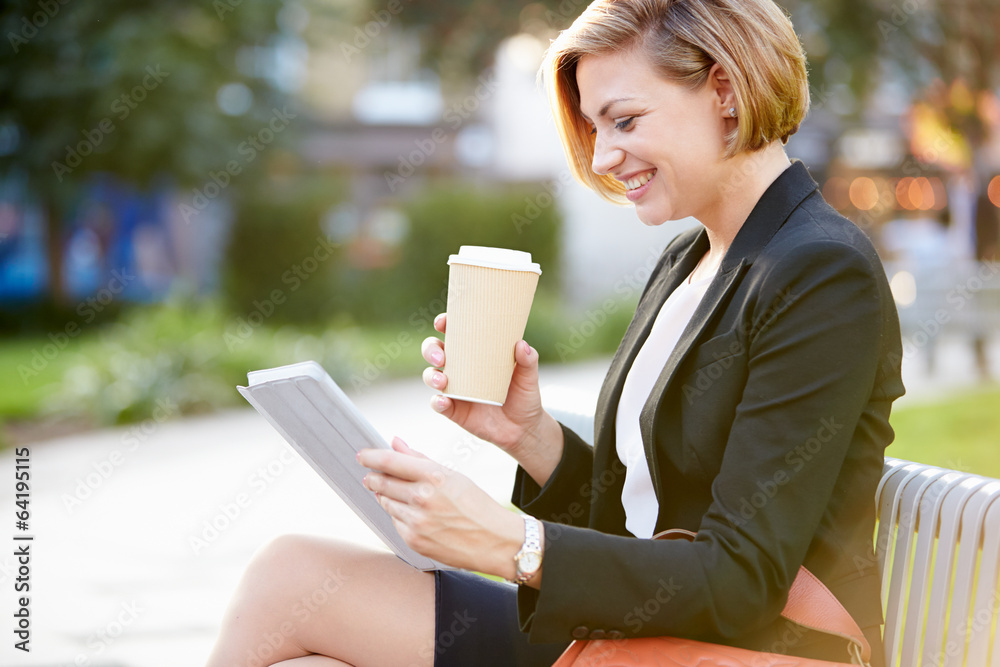 Businesswoman On Park Bench With Coffee Using Digital Tablet Businesswoman On Park Bench With Coffee Using Digital Tablet