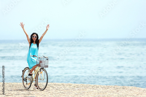 woman having fun riding bicycle at the beach