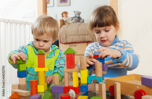 Two  tranquil children playing with wooden toys