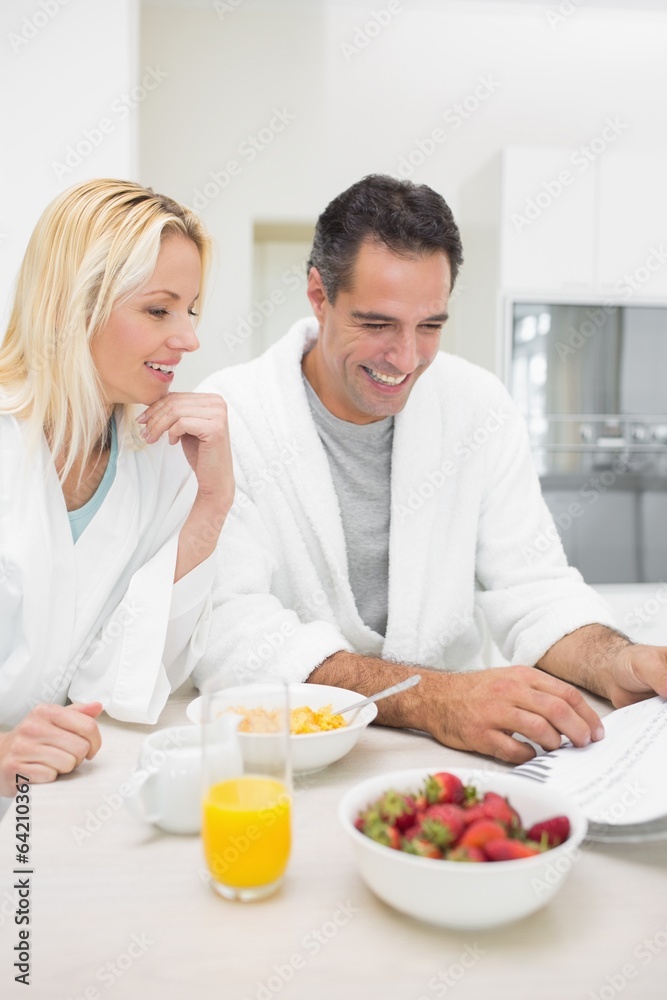 Couple having breakfast while reading newspaper in kitchen