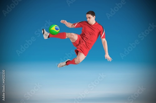 Composite image of fit football player jumping and kicking