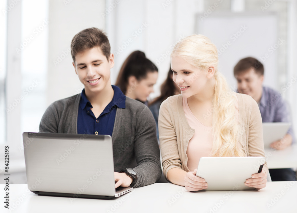 Fototapeta premium two smiling students with laptop and tablet pc