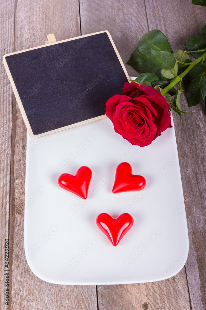 Fototapeta premium Tafel mit Herzen, Teller, Rose auf Schale