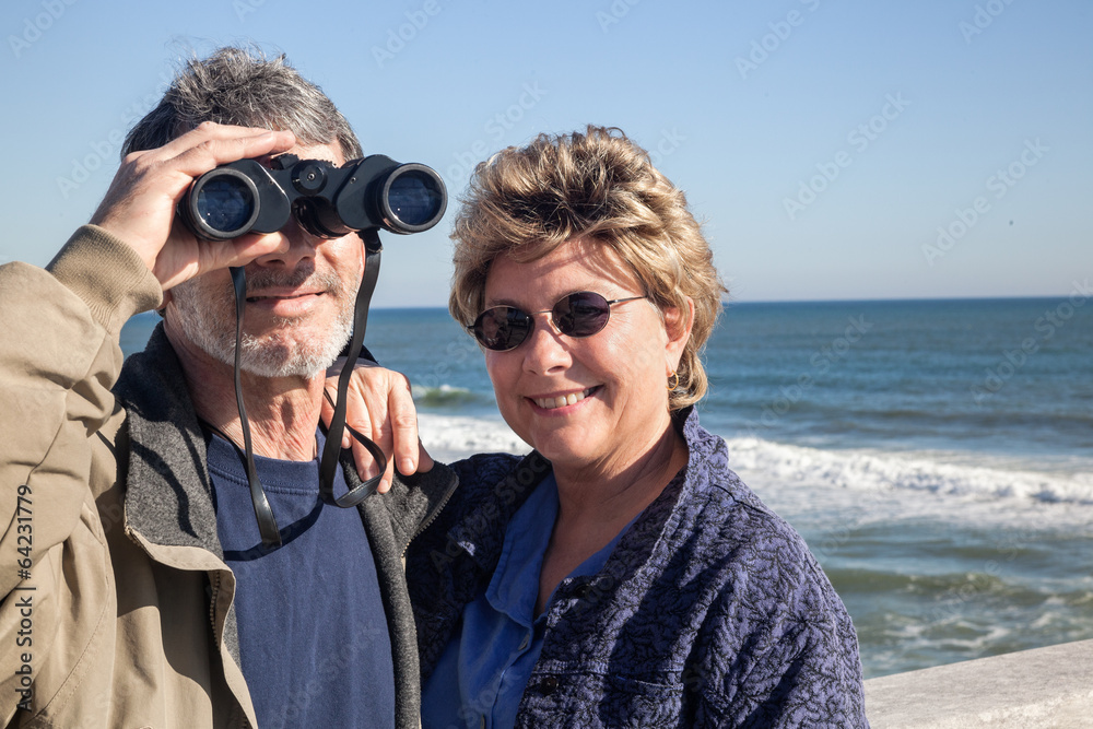 Retired couple on beach vacation with Binoculars