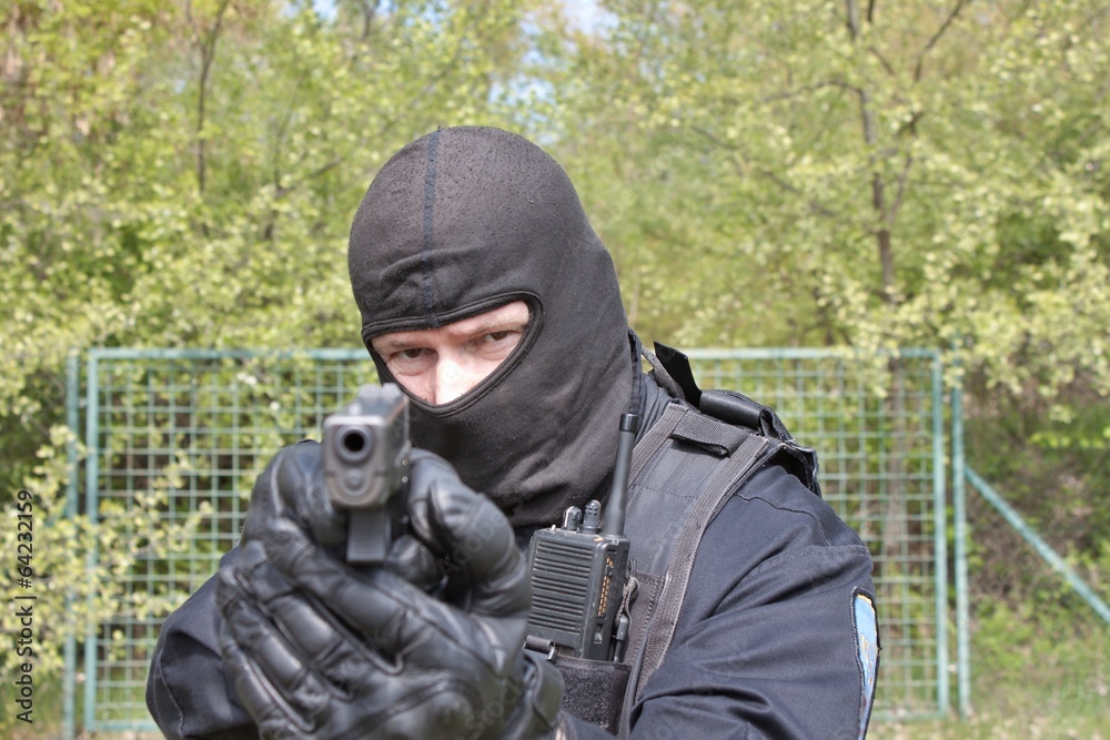 swat police officer pointing a gun at the camera, closeup Stock Photo