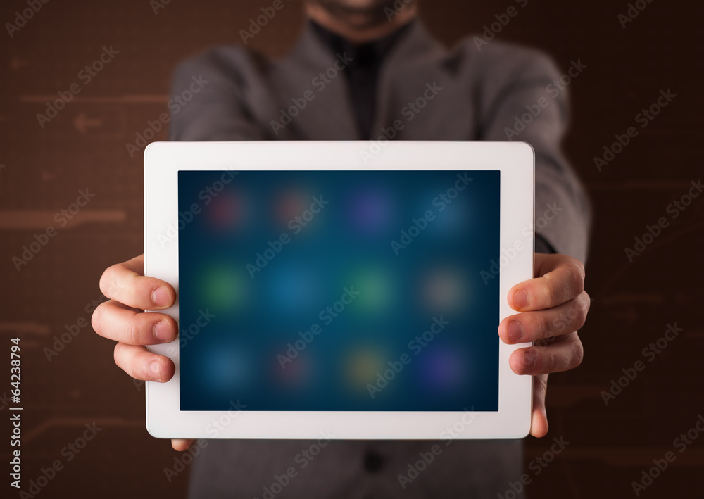 Businessman holding a white modern tablet with blurry apps Businessman holding a white modern tablet with blurry apps