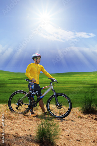young man standing beside moutain bike ,mtb on hill with sun shi