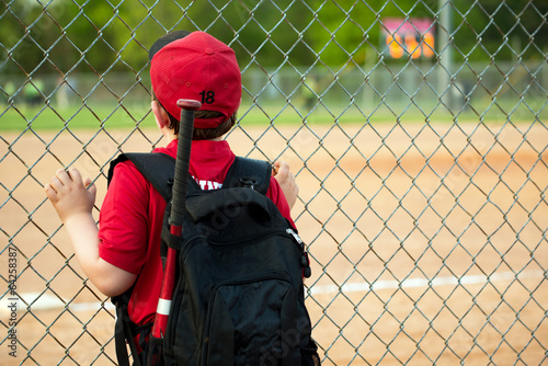 Photography Young baseball player watching game from outside fence