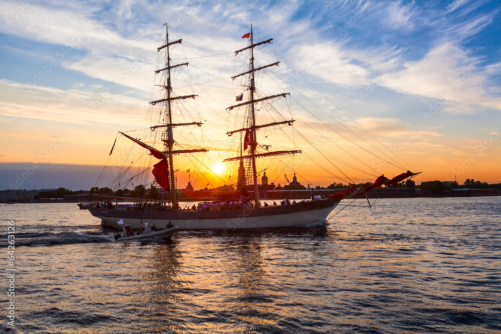 Sailing vessel in river water in rays of setting sun