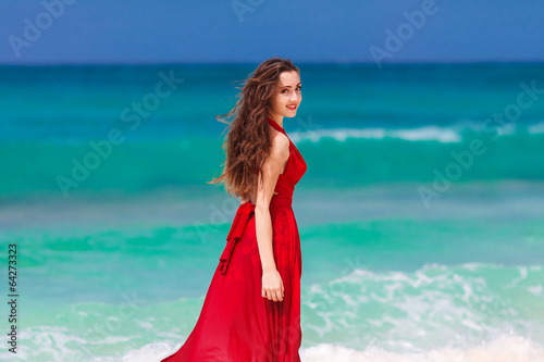 beautiful woman in a red dress  standing on the tropical sea co