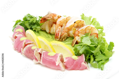 shrimp and tuna with greens and sauce on a white background