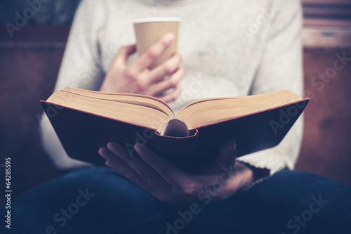 Man reading and drinking from paper cup