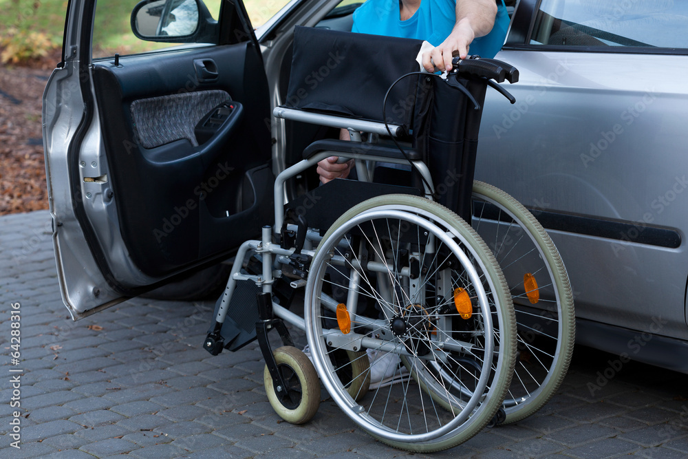 Man packing wheelchair into a car
