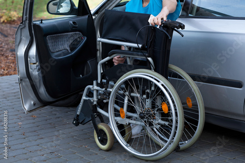 Man packing wheelchair into a car © Photographee.eu