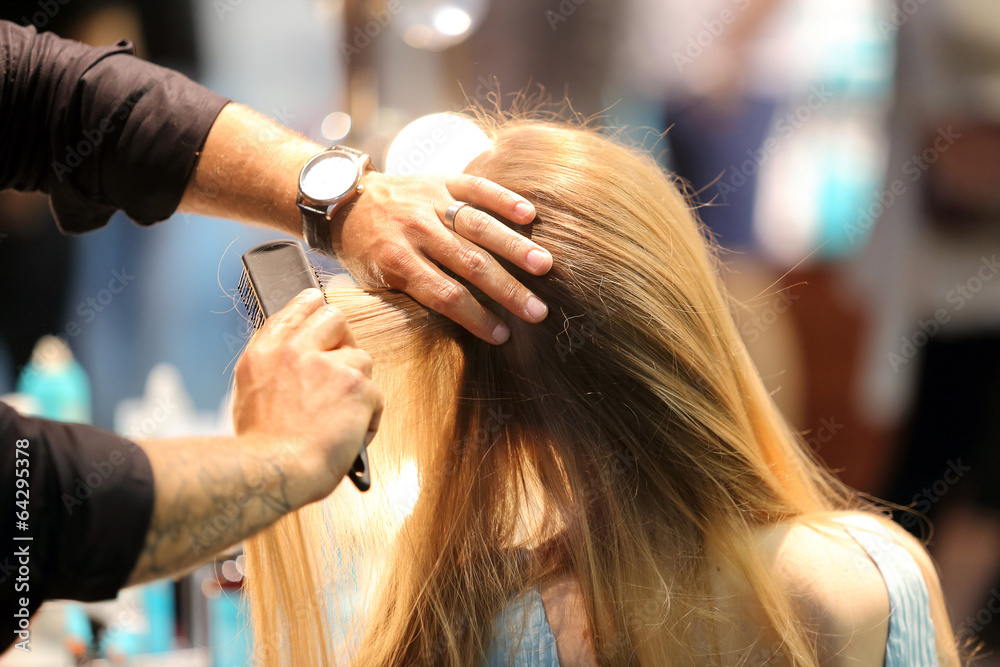 Fototapeta premium Hairdresser combing hair of young girl by hairbrush