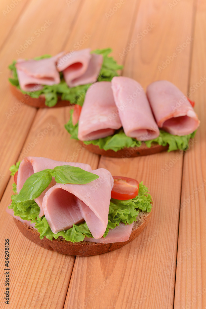 Delicious sandwiches with lettuce and ham on table close-up