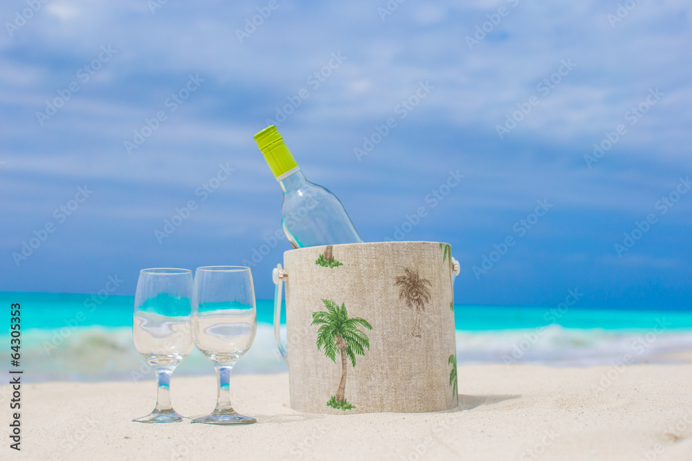 Bottle of white wine and two glasses on the exotic sandy beach Bottle of white wine and two glasses on the exotic sandy beach