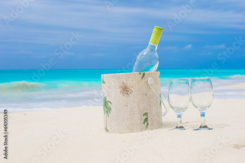 Bottle of white wine and two glasses on the exotic sandy beach